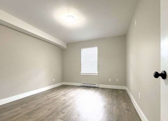 A room with a window and a wooden floor.