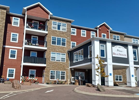 The image shows a multi-story residential building with a clear blue sky in the background.