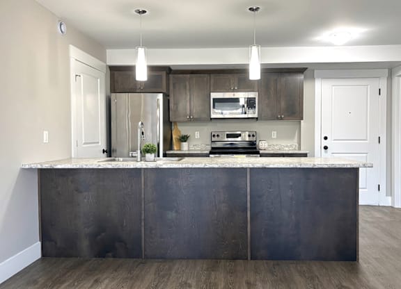 A modern kitchen with a dark island and stainless steel appliances.