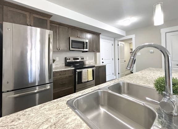 A kitchen with a stainless steel sink and refrigerator.
