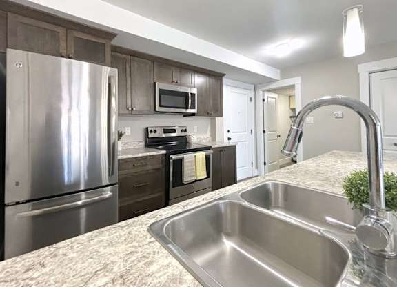A kitchen with a stainless steel sink and refrigerator.