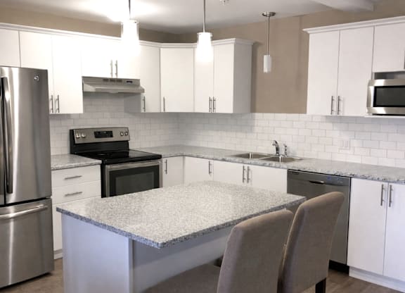 A kitchen with a granite countertop and stainless steel appliances.