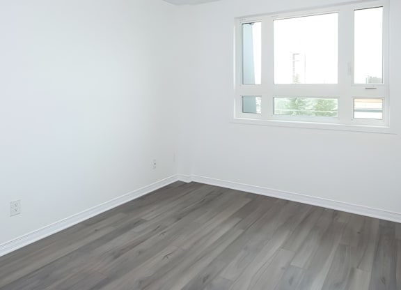 A room with a window and wooden flooring.