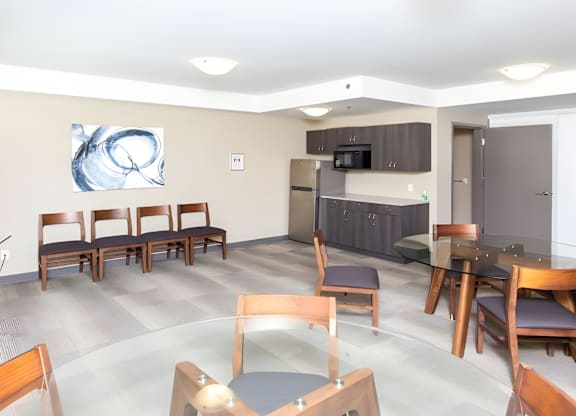 A modern dining room with a large painting on the wall and a kitchen area in the background.