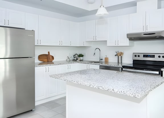 A modern kitchen with a stainless steel refrigerator and a marble countertop.