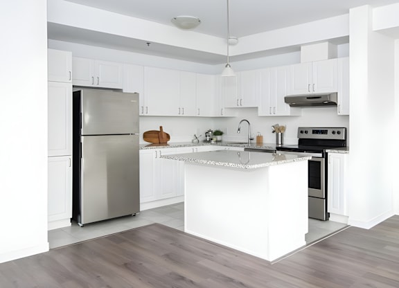 A modern kitchen with a stainless steel refrigerator and a white island.