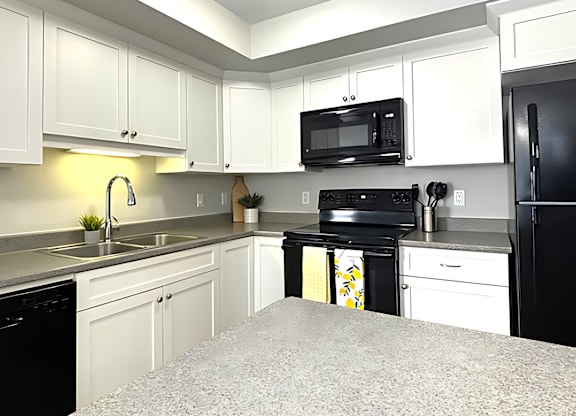 A kitchen with black appliances and white cabinets.