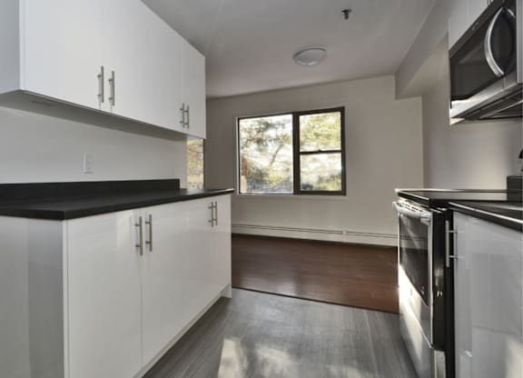 A modern kitchen with white cabinets and black countertops.