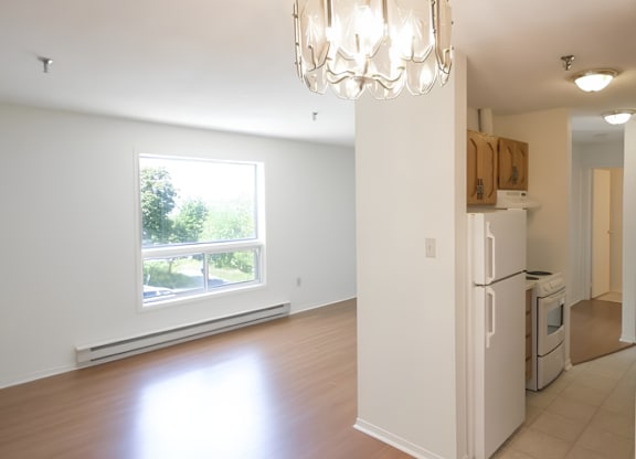A white kitchen with a large window and a chandelier.