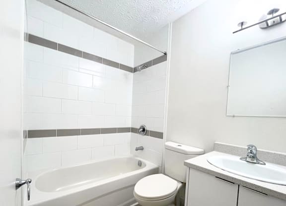 A white bathroom with a toilet, sink, and bathtub.