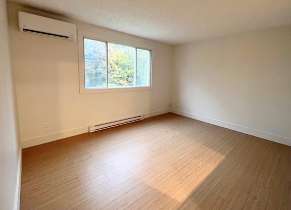 A room with a window and a wall-mounted air conditioner.