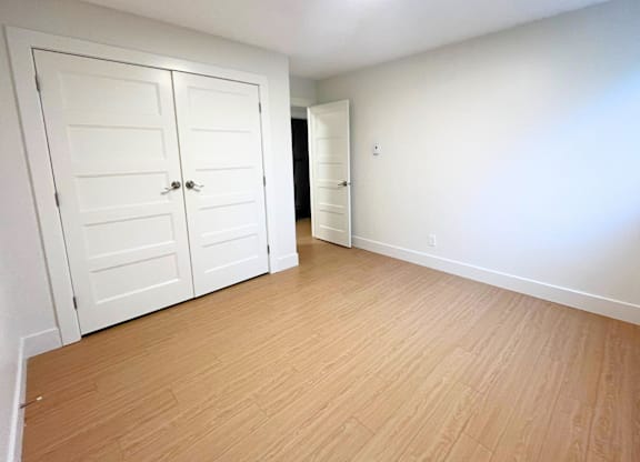 A room with a white door and a wooden floor.