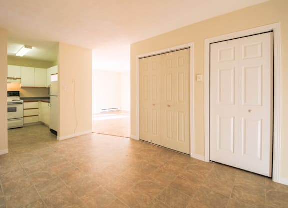 A room with two white doors and a kitchen in the background.
