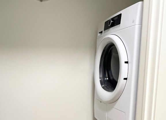 A white front loading washing machine in a laundry room.