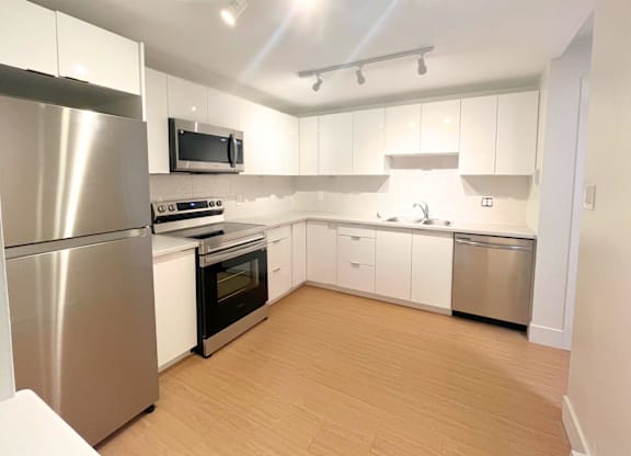 A kitchen with a refrigerator, oven, microwave, and sink.