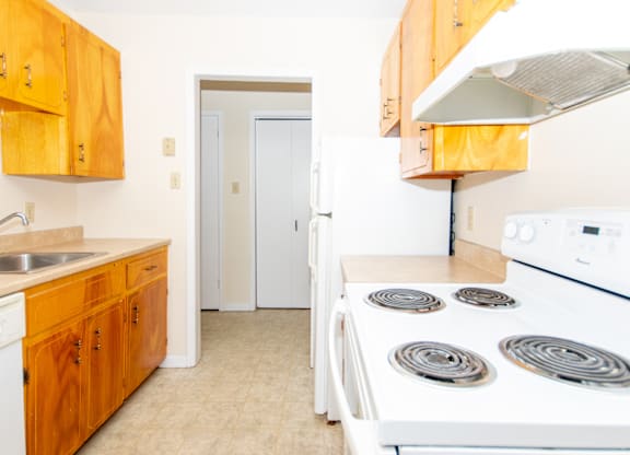 A kitchen with a white stove and wooden cabinets.