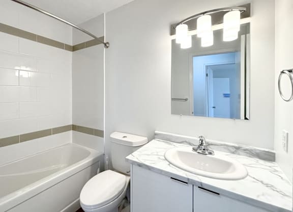 A white bathroom with a toilet, sink, and bathtub.