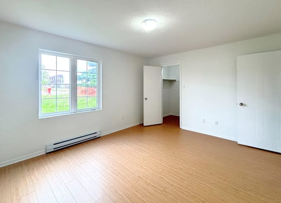 A room with a window, a door, and a wall-mounted shelf.