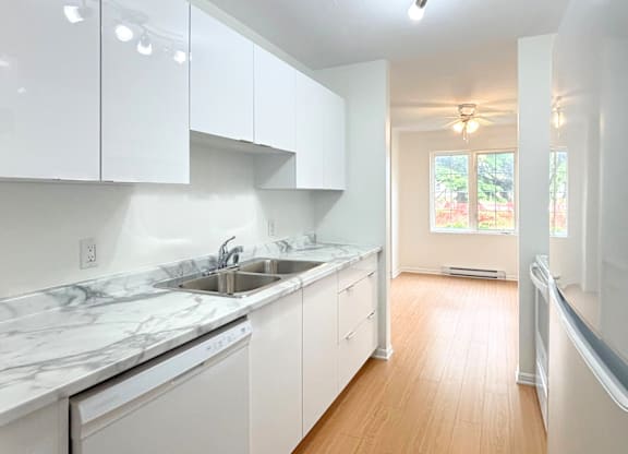 A kitchen with white cabinets and marble countertops.