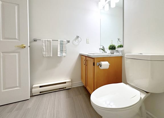 A white toilet sits in a bathroom with a white door and a mirror.