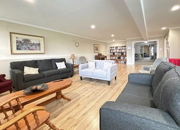 A living room with a grey couch, a wooden coffee table, and a painting on the wall.