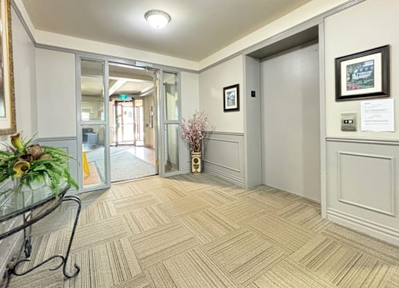 A hallway with a glass table and a plant on it.
