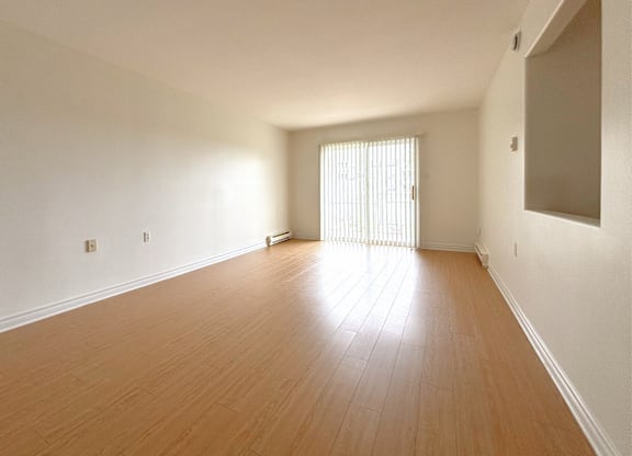 A room with wooden flooring and a window with blinds.