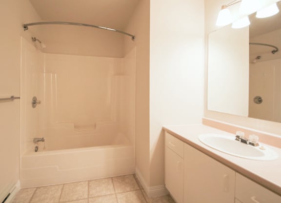 A white bathroom with a tub, sink, and mirror.