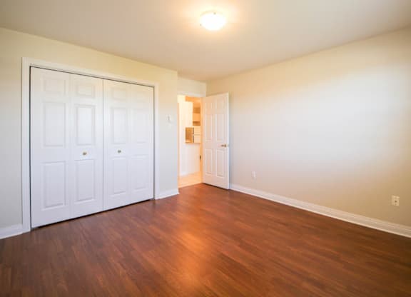 A room with a white door and wooden floors.