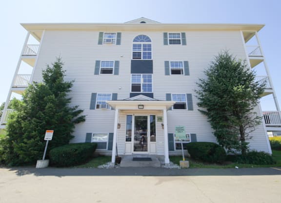A two-story building with a white facade and a covered entrance.