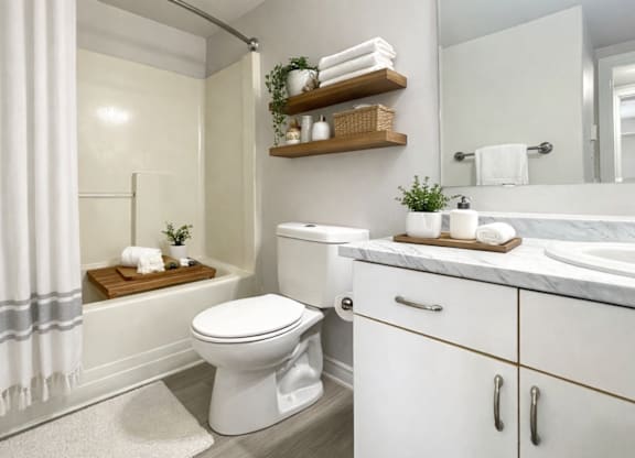 A white toilet sits in a bathroom next to a sink and a shower.