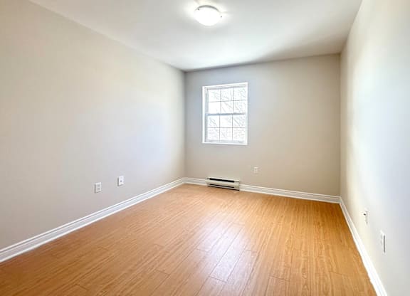 A room with a window and wooden flooring.