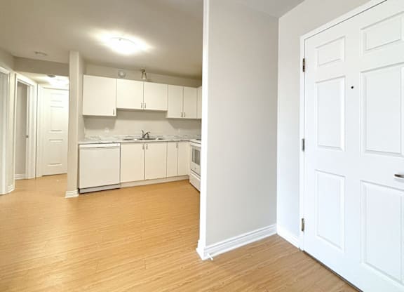 A kitchen with white cabinets and a wooden floor.