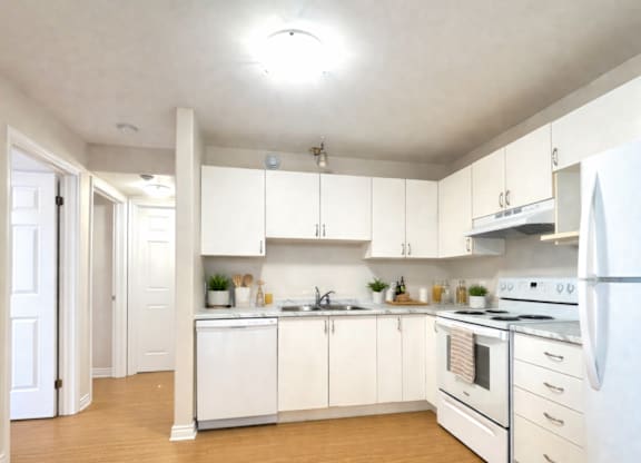 A kitchen with white appliances and wooden floors.