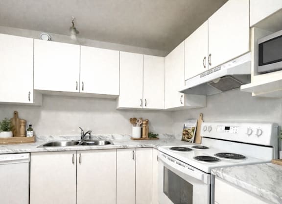 A white kitchen with a stove, sink, and cabinets.