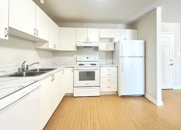 A white kitchen with wooden floors and white appliances.