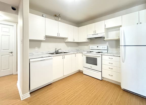 A white kitchen with wooden floors and white appliances.