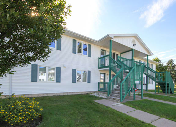 A white house with green railings and a green staircase.