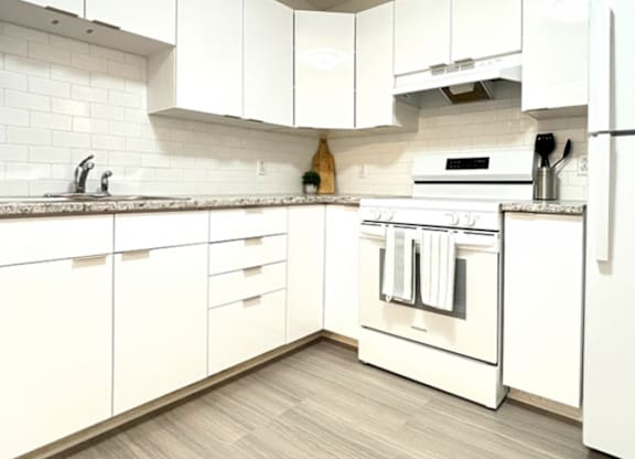 A white kitchen with a stove and a refrigerator.