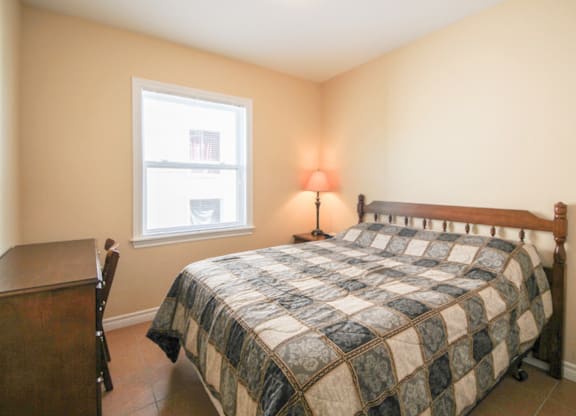 A bedroom with a bed, nightstand, and window.