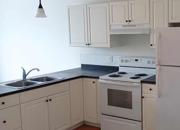 A white kitchen with a black counter top and white appliances.