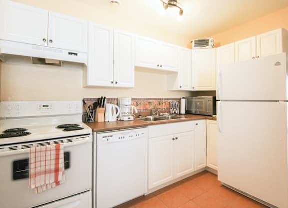 A kitchen with white appliances and cabinets.