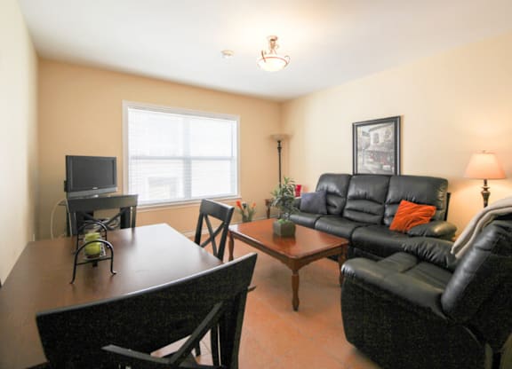 A living room with a black leather couch and a wooden coffee table.