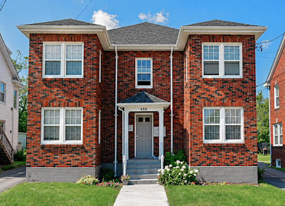 A red brick house with a grey roof and a white door.