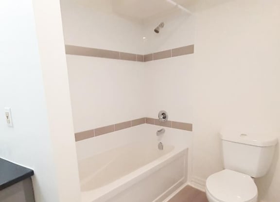 A white toilet sits next to a bathtub in a bathroom.