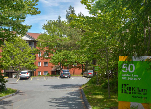 A green and yellow sign for Killam Apartment Rent is on the side of a road.