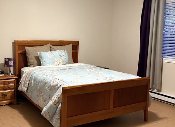 A bed with a wooden headboard and a blue floral comforter.