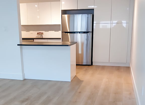 A kitchen with a white counter and a black fridge.