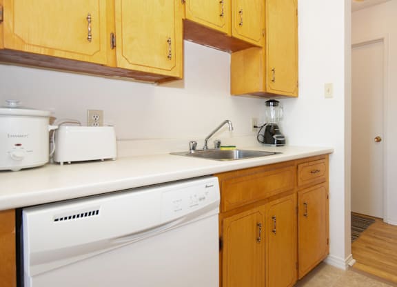 A kitchen with wooden cabinets and a white dishwasher.