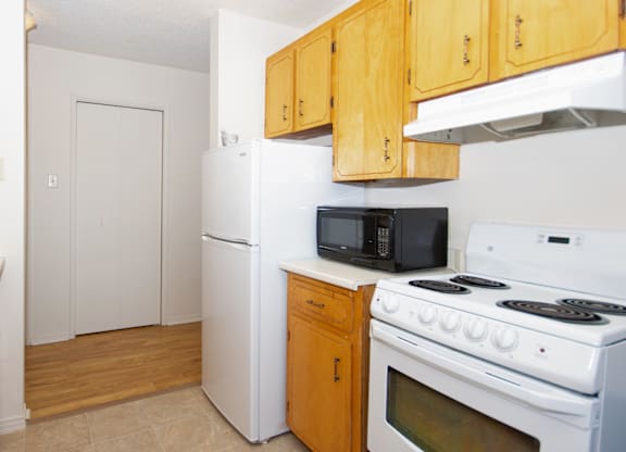 A kitchen with white appliances and wooden cabinets.